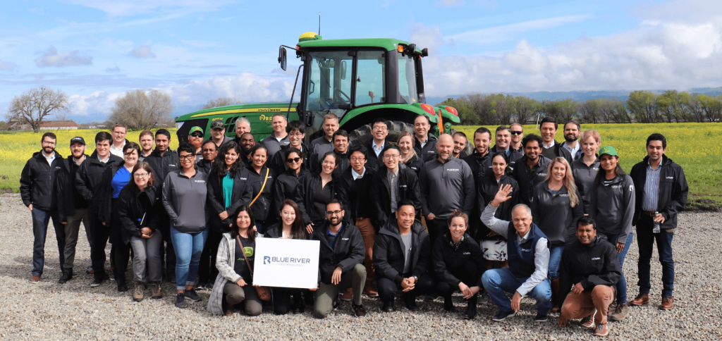 Students and Blue River staff in front of a tractor in an open field