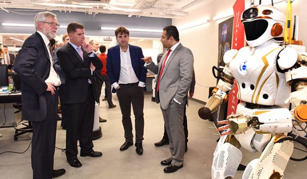 Fady Saad speaks with a group of men next to a humanoid robot