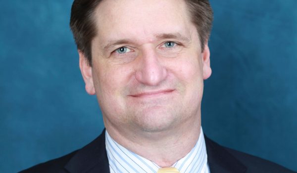 Portrait of Bryan Moser, a white man in a suit and yellow tie