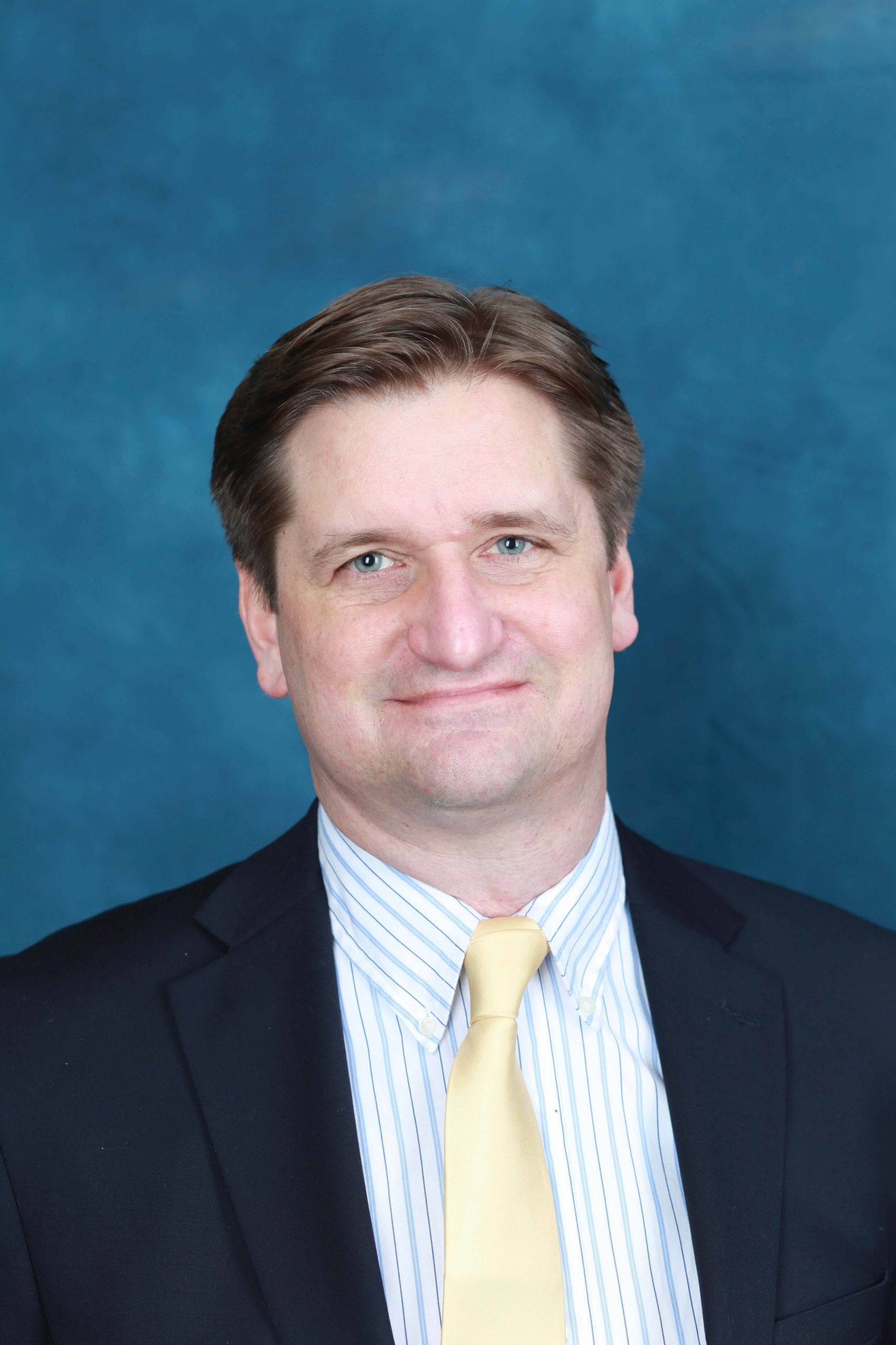 Portrait of Bryan Moser, a white man in a suit and yellow tie