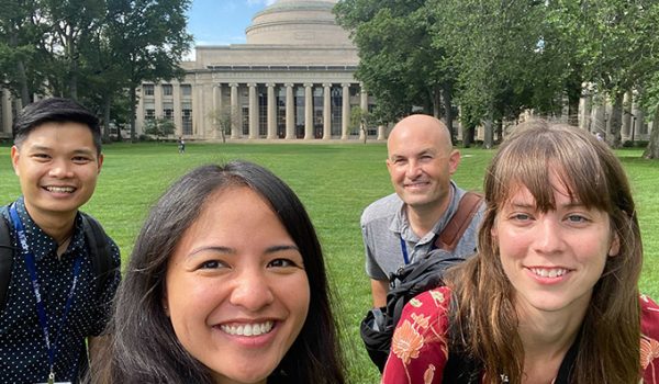 Four students smile with the MIT Dome in the background