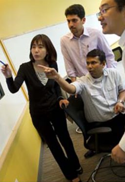 A group of students looking at a whiteboard, with two pointing out various items