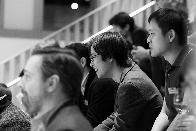 A black-and-white photo of students seen in profile, listening to an unseen speaker.