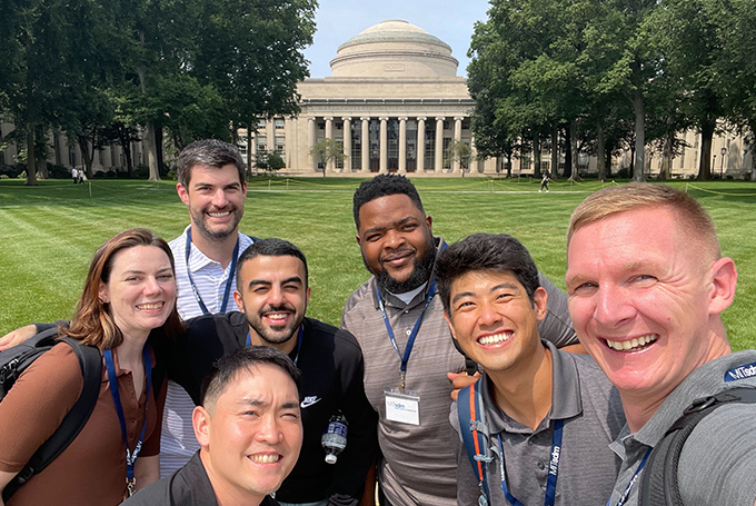 A group of students smiling in front of the MIT Dome.