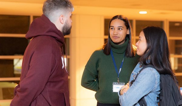 Three students, standing and chatting.