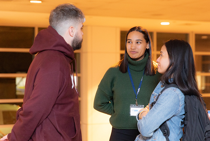 Three students, standing and chatting.